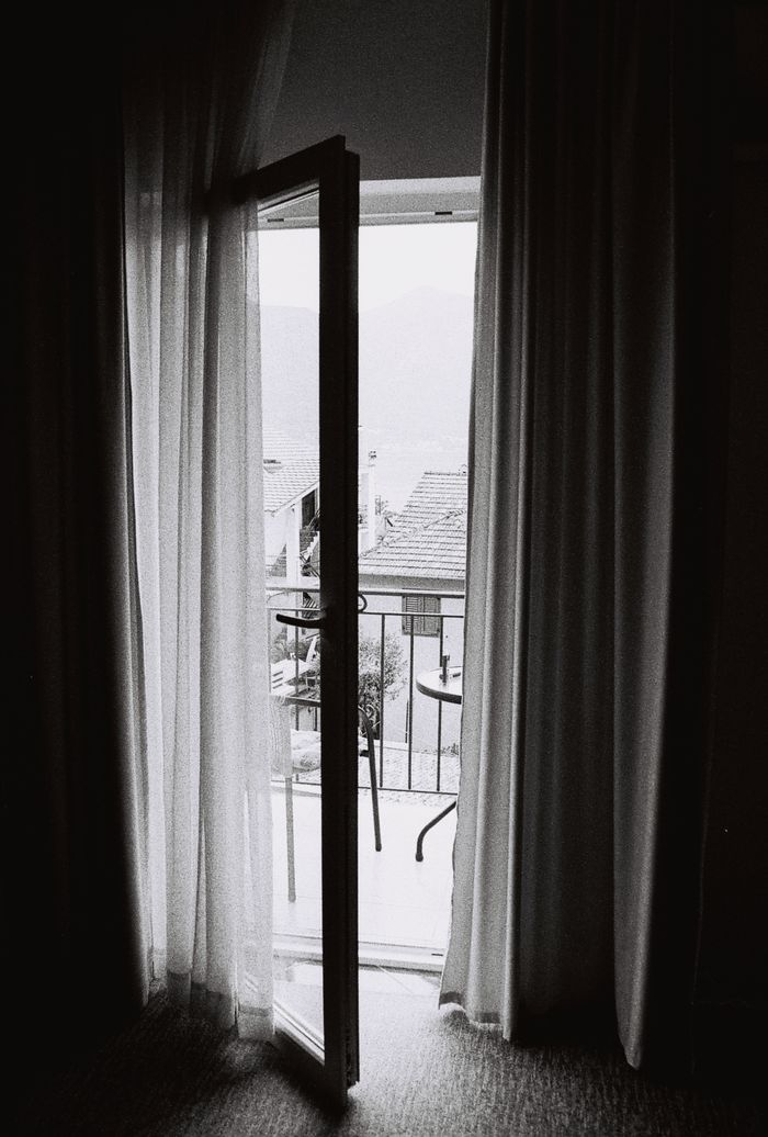 portfolio-01 Black and white photo of an open door leading to a balcony in Kotor, Montenegro.