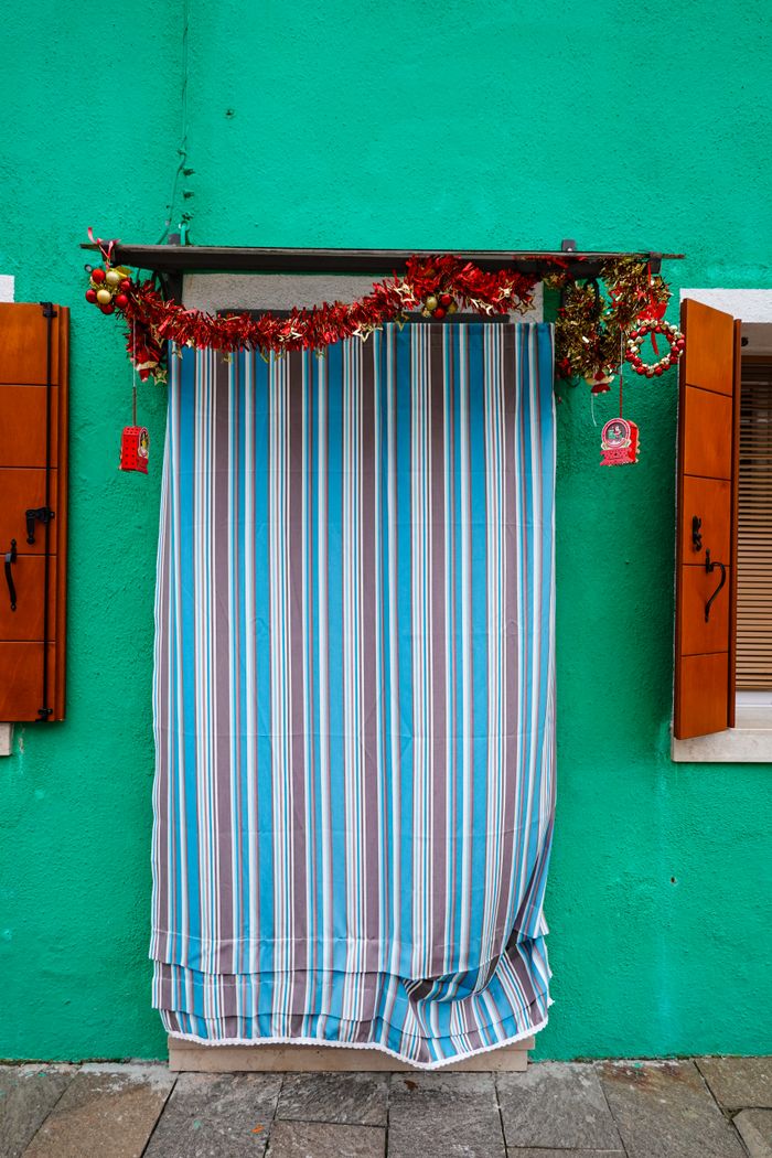 services-01 A vibrant turquoise wall with a striped curtain covering the entrance.