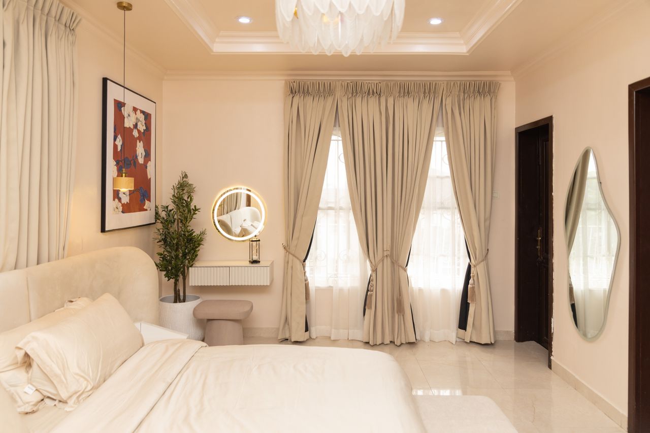 gallery-06 Stylish bedroom with beige decor, soft lighting, and modern furnishings.